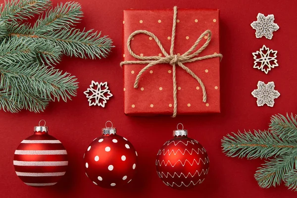Composición navideña. Regalos ramas de árbol de Navidad y adornos sobre fondo rojo — Foto de Stock