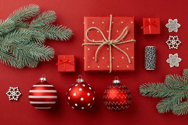 Composición navideña. Regalos ramas de árbol de Navidad y adornos sobre fondo rojo — Foto de Stock