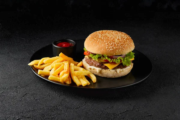 Świeży smaczny burger, frytki i ketchup na ciemnym tle — Zdjęcie stockowe