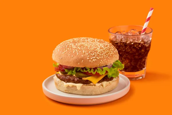 Свіжий смачний бургер і безалкогольний на апельсиновому фоні — стокове фото