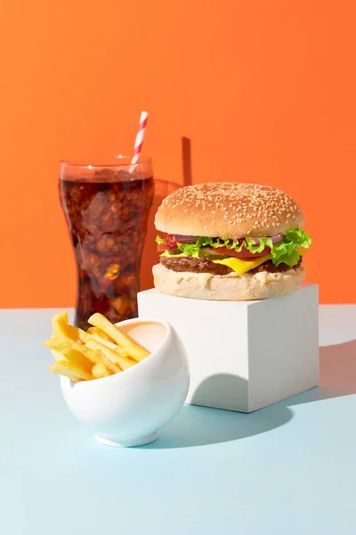 Klasický tradiční cheeseburger, hranolky a limonádový nápoj na oranžovém a modrém pozadí. Menu grilu BBQ — Stock fotografie