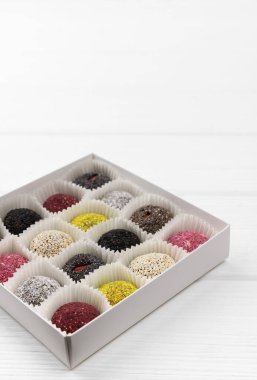 Bir kutu vejetaryen şekeri enerji topları beyaz ahşap masada..