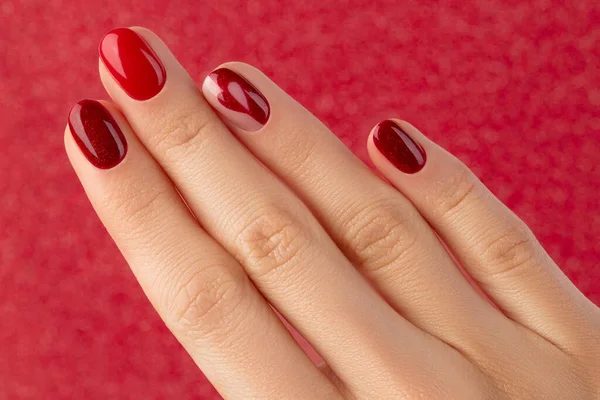 Mano femminile con manicure su sfondo rosso — Foto Stock