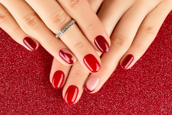 Mani femminili con manicure su sfondo rosso — Foto Stock