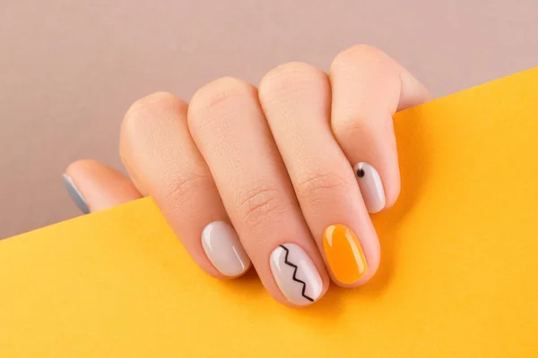Närbild kvinnors hand med trendig minimal manikyr på orange bakgrund. Höstens nageldesign — Stockfoto