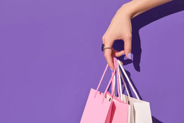 Ženská ruka drží papírové nákupní tašky na fialovém pozadí. Koncept dodání nákupního prodeje — Stock fotografie