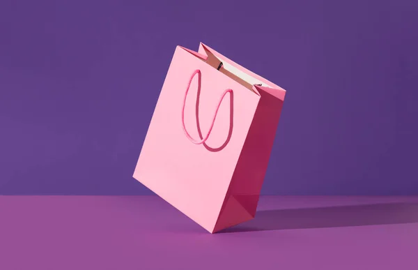 Pink flying paper shopping bag on purple background. Shopping sale delivery concept — Stock Photo, Image