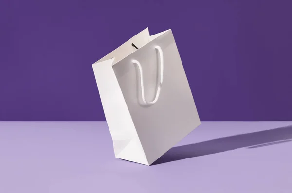 White floating paper shopping bag on purple background. Shopping sale delivery concept — Stock Photo, Image