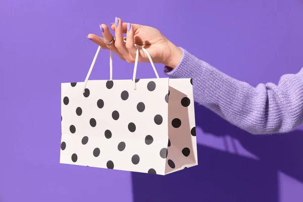 Dámské ruce drží bílou papírovou nákupní tašku na fialovém pozadí. Koncept dodání nákupního prodeje — Stock fotografie