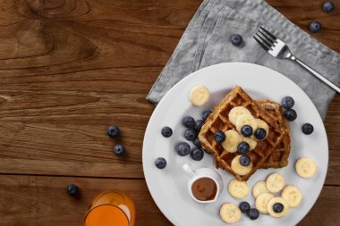 Kırsal ahşap masada muzlu ve yaban mersinli Belçika waffle 'ı. Sağlıklı kahvaltı diyet tarifi