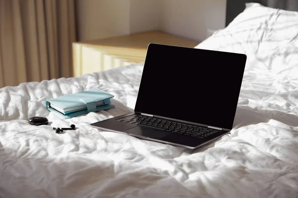 Ноутбук, планувальник і навушники на ліжку на сонячному світлі — стокове фото