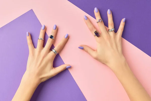 Hermosas manos de las mujeres con diseño de uñas de primavera de moda púrpura sobre fondo rosa púrpura —  Fotos de Stock