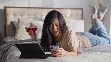 Ciddi bir kadın, günlük giysiler içinde dijital tablette yatarken görüntülü konuşma yapıyor.