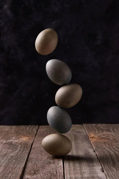 Balancing dyed eggs on wooden table. Easter celebration concept — Stock Photo, Image