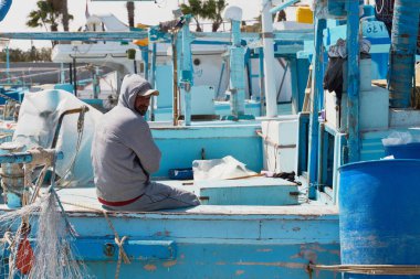 HURGHADA, EGYPT - 19 Şubat 2022: Balıkçılık için denize açılmadan önce teknede oturan yerel balıkçı