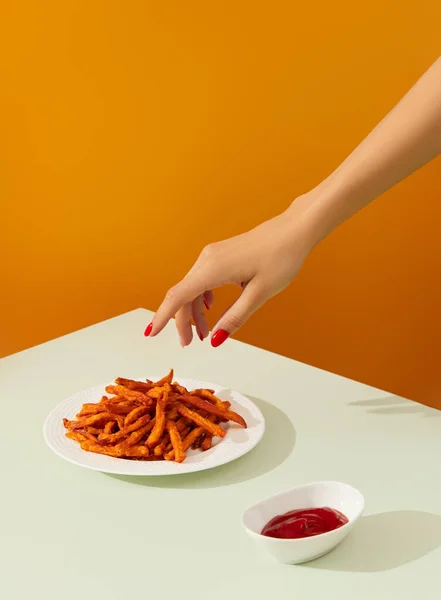 Kadınların eli yeşil masada patates kızartması yer. Vegan alternatif yemek tarifi.