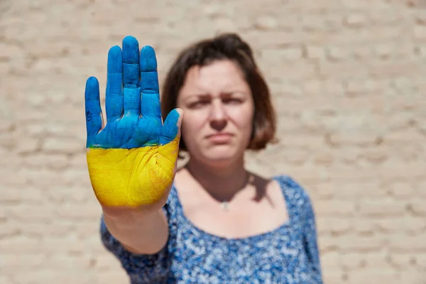 Mujer ucraniana con un símbolo de la bandera en su mano muestran señal de stop contra el cielo azul. Alto a la guerra — Foto de Stock