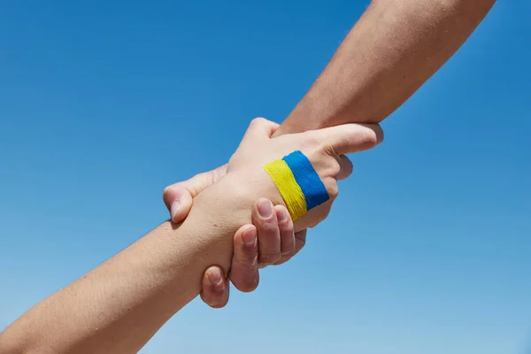 借一只手帮助画在乌克兰国旗的颜色与蓝天的对比。与乌克兰站在一起 — 图库照片