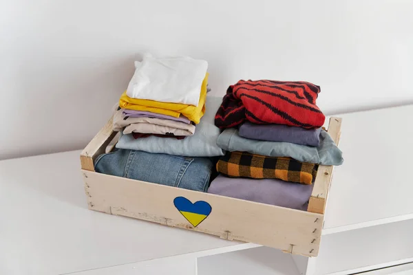 Help volunteering donation concept. Donation box full of clothes at home — Stock Photo, Image