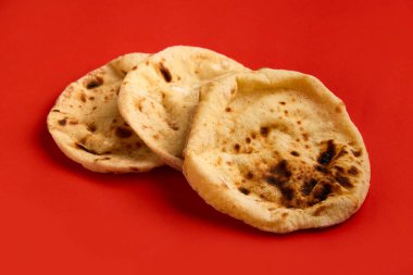 Mısır ekmeği Aish Baladi. Kırmızı masada bir sürü taze ekmek yatıyor.