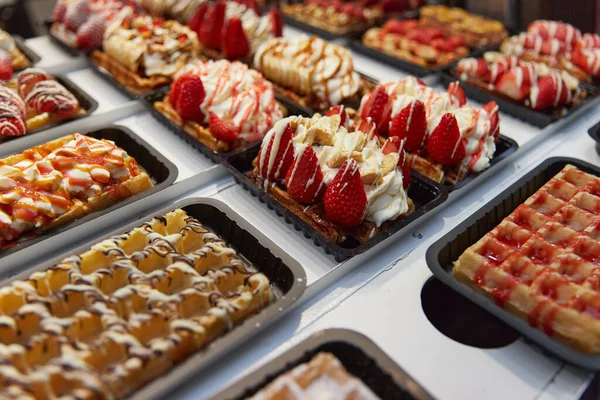 Різні традиційні бельгійські вафлі з шоколадом, спекулами, збитими вершками і фруктовим дисплеєм на березі магазину в Брюсселі. — стокове фото