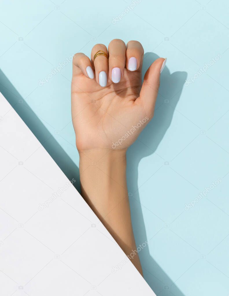 Womans hands with trendy manicure on blue background. Summer nail design
