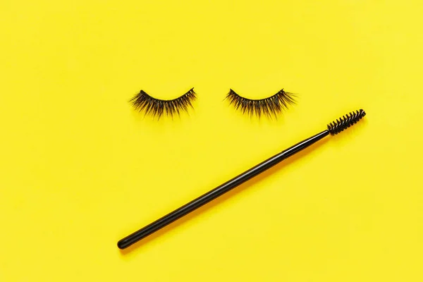 Kreatives Layout mit Wimpern und Pinselmascara. Geschlossene Augen auf gelbem Hintergrund — Stockfoto