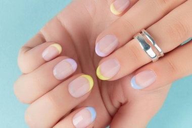 Manikürlü kadınların ellerini mavi arka plana koy.