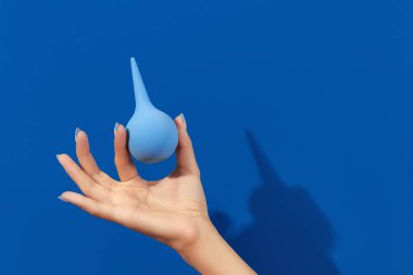 Mavi arka planda lavman tutan bakımlı kadınlar.