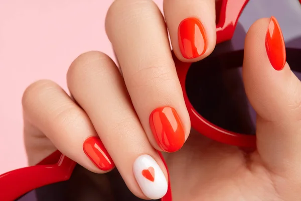 Manicured womans hand holding sunglasses. Fashionable valentines day nail design — Photo