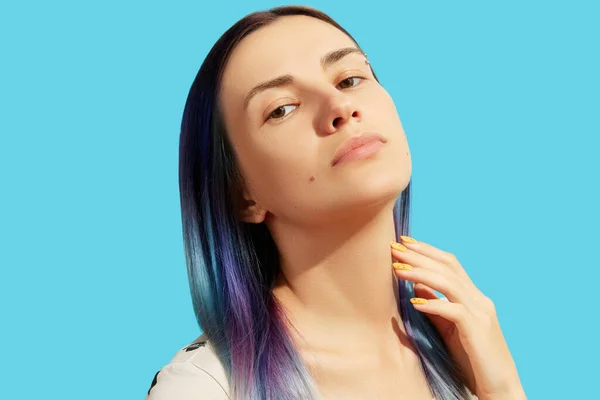 Beautiful woman with blue hair touch her neck on bright background — стоковое фото