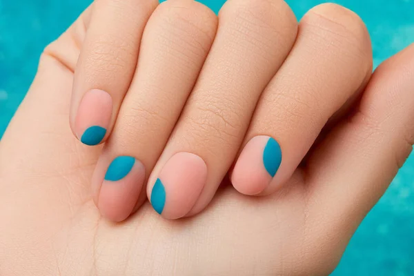 Feche a mão de mulheres com a manicura de verão no contexto azul. Tendências de design de manicure — Fotografia de Stock