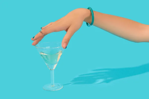 Krásné upravené ženy ruku s módní prsten dotykové sklo koktejl na modrém pozadí — Stock fotografie