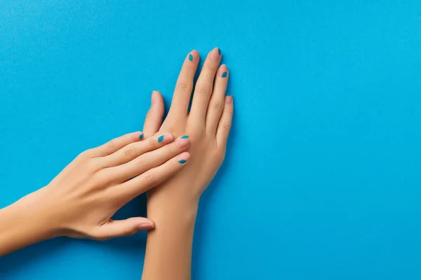 Mani delle donne con manicure estiva su sfondo blu — Foto Stock