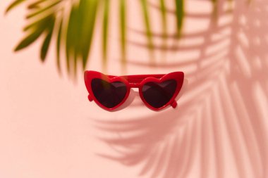 Kırmızı kalp, pembe arka planda güneş gözlüğü şeklinde.