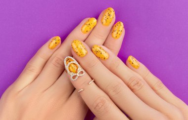 Mor arka planda moda tırnak tasarımı olan manikürlü kadın elleri