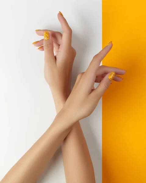 Gepflegte Frauen mit trendigem Nageldesign auf orangefarbenem Hintergrund — Stockfoto