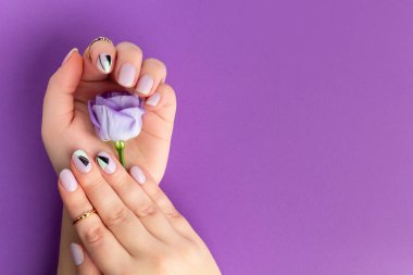 Menekşe arka planında bahar tasarımı olan güzel kadınların elleri. Manikür, pedikür güzellik salonu konsepti