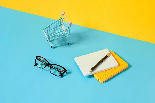 Smartphone Schreibwaren Brille Und Einkaufswagen Über Den Blauen Tisch Zurück — Stockfoto