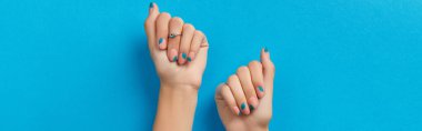 Mavi arka planda yaz manikürü olan kadın elleri. Manikür tasarım eğilimleri