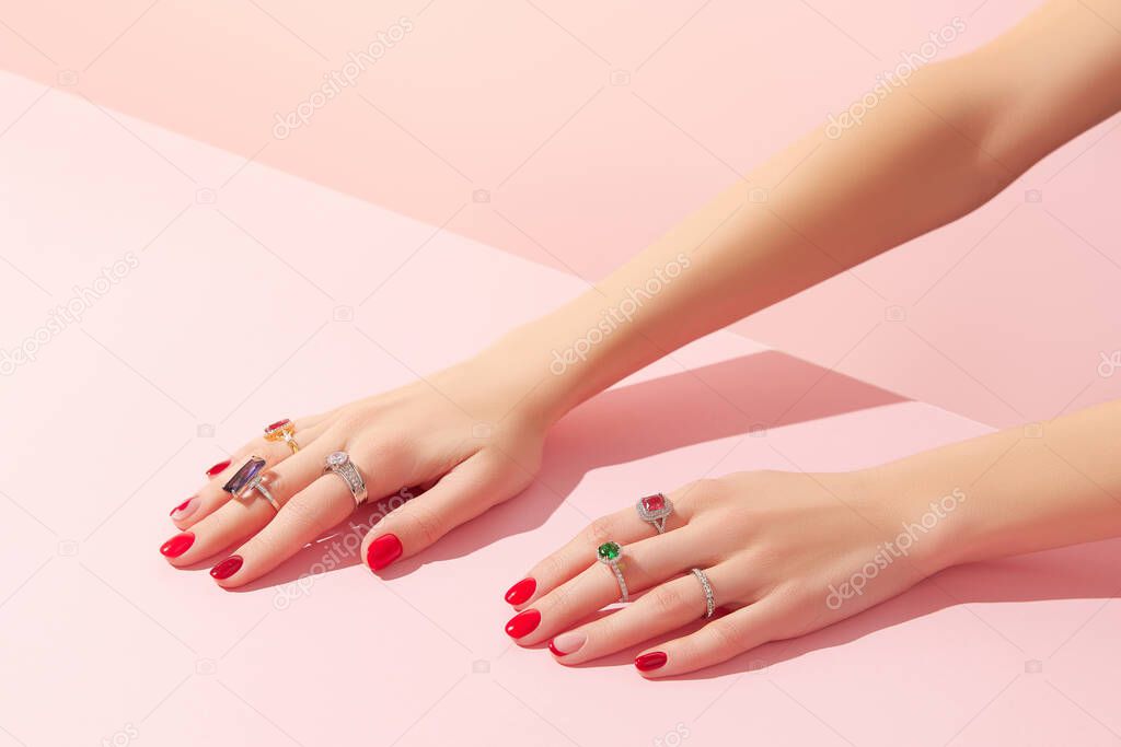 Womans hand with rinds on pink background. Jewelry accessory sale concept.