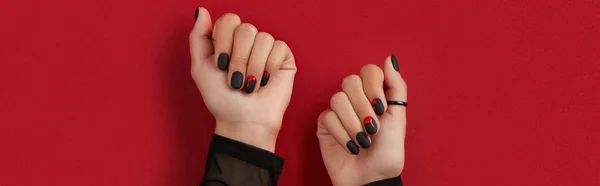 Manicured female hands with fashion accessories on red background. Trendy autumn halloween bloody spooky nail design.