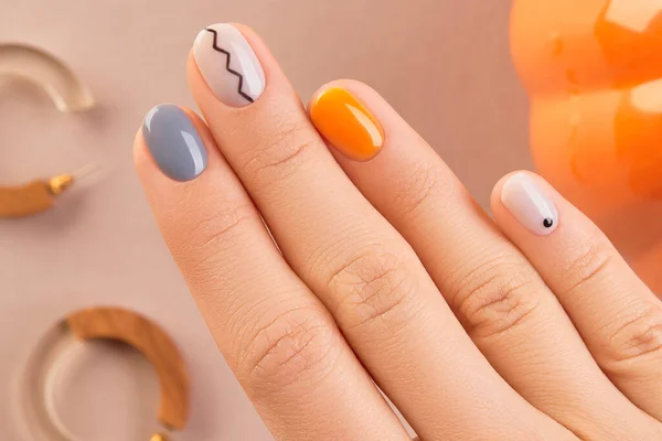 Manicured womans hand close up on beige background. Minimal spring autumn nail design. Beauty treatment body care concept