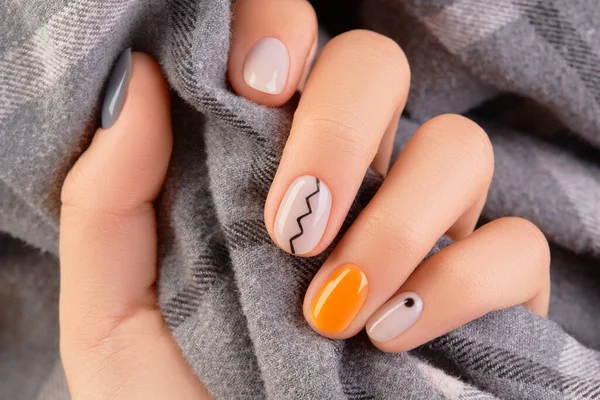 Manicured womans hand close up on gray background. Minimal spring autumn nail design. Beauty treatment body care concept