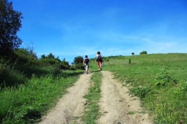 Anne ve oğul yeşil tepenin yolunda yürüyor..