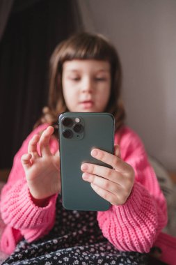 Şirin küçük bebek. Pembe hırkalı, uzun saçlı 5 yaşında kız. Akıllı telefondan büyük bir ilgiyle mesaj atıyor.