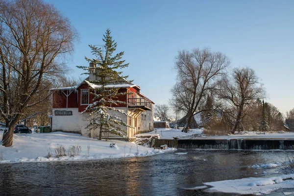 古い工場は晴れた冬の日に小さなエストニアの都市のパブとして運営されていた 建物の前にある美しい滝と川 — ストック写真