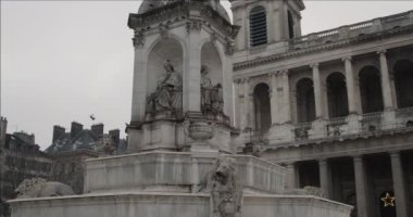 Bulutlu bir kış gününde Saint-Sulpice Kilisesi 'nin önünde güzel bir çeşme. Bir çeşme güvercinlerle çevrilidir.