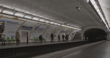Metro treni Sevres Babylone istasyonuna varmak üzere. Tren bekleyen yüz maskesi takan insanlar. Paris metrosu Avrupa 'nın en işlek ikinci metro sistemidir..