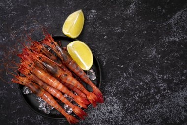 Siyah tahtada kırmızı büyük kral karideslerin üst görüntüsü. Boşluğu kopyala.